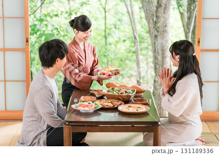 温泉旅館の客室で料理の説明をする旅館スタッフ・仲居さんの女性 温泉旅館の客室で料理の説明をする旅館スタッフ・仲居さんの女性 131189336