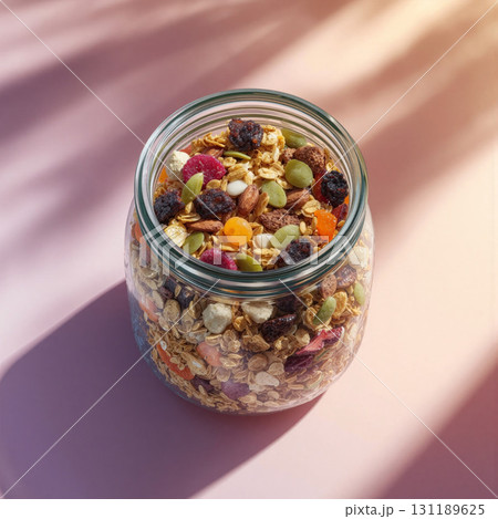 Glass jar filled with colorful layers of healthy snacks on a soft background with natural light 131189625