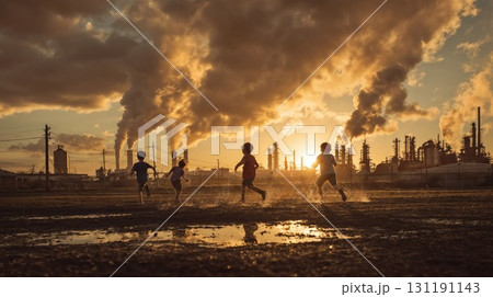 Children play in puddles at sunset in front of a large industrial factory with smoke billowing from the stacks, highlighting the issue of pollution and climate change Children play in puddles at sunset in front of a large industrial factory with smoke billowing from the stacks, highlighting the issue of pollution and climate change 131191143
