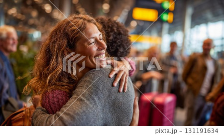 Joyful reunion embrace between two women at busy airport terminal with luggage showing emotional homecoming and travel connection moment 131191634