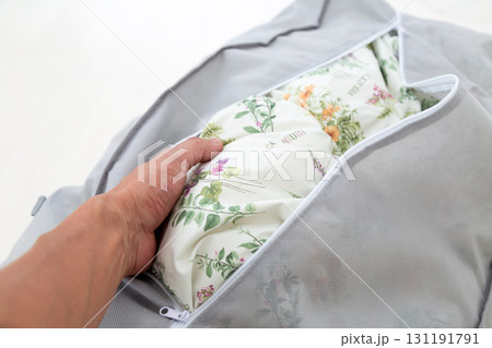 布団収納袋に入った羽毛の掛け布団を取り出す 131191791