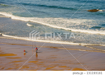 Angler with fishing rod on sea shore 131193181