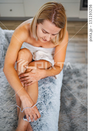 Woman removing leg hair with an electric epilator at home 131193256