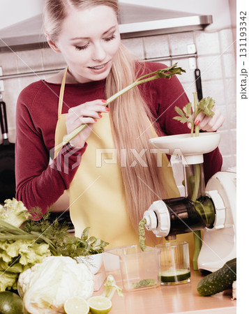 Woman in kitchen making vegetable smoothie juice Woman in kitchen making vegetable smoothie juice 131193342