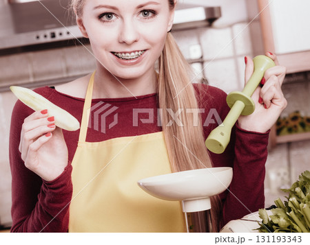 Woman in kitchen making vegetable smoothie juice Woman in kitchen making vegetable smoothie juice 131193343