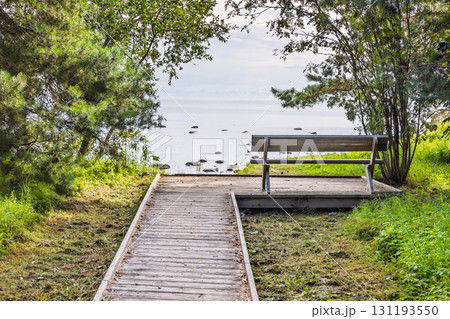 Tranquil Baltic coast with wooden path and bench overlooking serene blue seascape Tranquil Baltic coast with wooden path and bench overlooking serene blue seascape 131193550