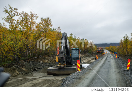 Excavator working on road construction site in autumn forest 131194298