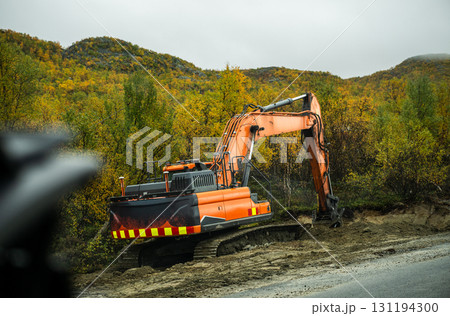 Excavator working on road construction in autumn forest landscape 131194300