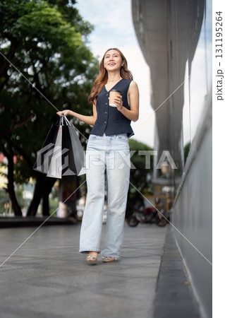 Shopping Delight. Young woman enjoying a stroll with shopping bags and coffee. Shopping Delight. Young woman enjoying a stroll with shopping bags and coffee. 131195264