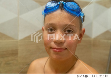 Young boy wearing blue swimming goggles indoors 131195516