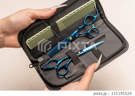 Hairdresser holding professional grooming kit with blue shears 131195520