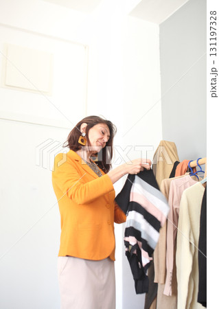an adult woman picking clothes in her wardrobe, lifestyle people concept 131197328