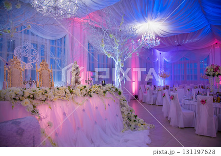 Elegant wedding reception with beautiful decorations and soft lighting in a charming venue Elegant wedding reception with beautiful decorations and soft lighting in a charming venue 131197628