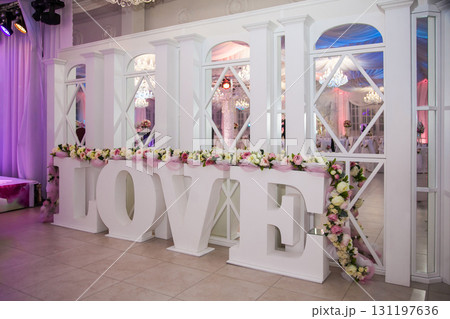 Large decorative love sign at a wedding venue decorated with flowers and soft lights in the evening 131197636