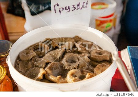 Inscription on the price tag: Grusdi - means Milk mushrooms: Altai pickled mushrooms in a plastic bucket at the fair Inscription on the price tag: Grusdi - means Milk mushrooms: Altai pickled mushrooms in a plastic bucket at the fair 131197646