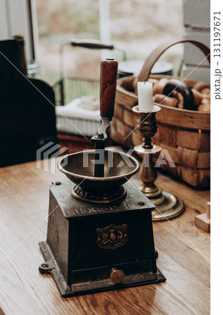 Vintage coffee grinder on wooden table near candle and basket of rolls in cozy space Vintage coffee grinder on wooden table near candle and basket of rolls in cozy space 131197671