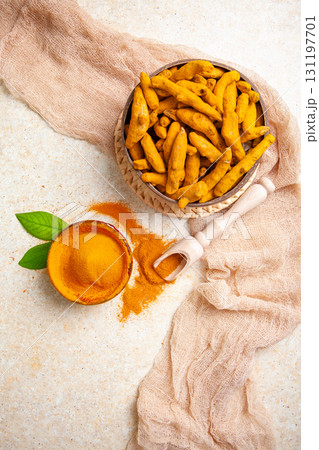 Dried turmeric roots and powder with leaves on a light background 131197701