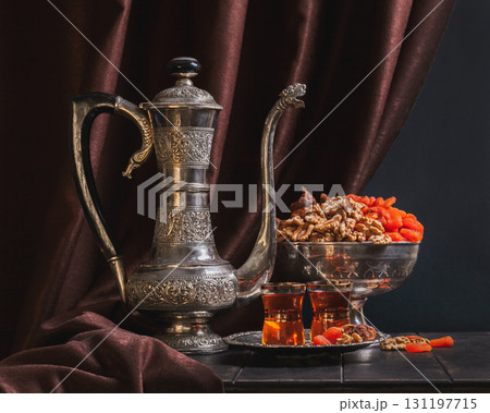 Ancient East metallic crockery - vintage jug for tea, vase with dried fruit and plate with tea in glasses 131197715