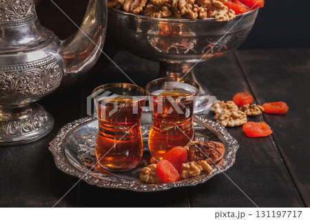 Plate with tea in armuda glasses, vintage jug, a vase with dried fruit - Ancient East metallic crockery 131197717