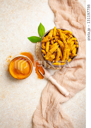 Dried turmeric roots and powder with leaves on a light background Dried turmeric roots and powder with leaves on a light background 131197786