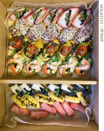 Box with small sandwiches with cold cuts, grilled vegetables, cheese and seafood. Charcuterie boards to order Box with small sandwiches with cold cuts, grilled vegetables, cheese and seafood. Charcuterie boards to order 131197834