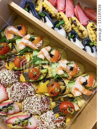 Box with small sandwiches with cold cuts, grilled vegetables, cheese and seafood. Charcuterie boards to order 131197836