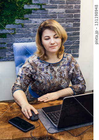 A young woman interior designer is working in her office at a computer. Green office, live plants in an office space A young woman interior designer is working in her office at a computer. Green office, live plants in an office space 131198948