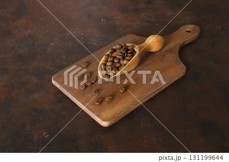 Coffee beans in a wooden scoop isolated on a dark background. Roasted coffee beans isolated. A wooden scoop with coffee. 131199644