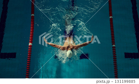 Swimmer mastering butterfly stroke with powerful arm extension in competitive lane Swimmer mastering butterfly stroke with powerful arm extension in competitive lane 131199885