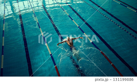 Focused swimmer executing butterfly stroke in indoor lane with powerful energy 131199886