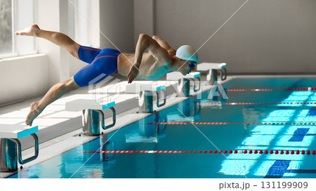 Male swimmer diving into pool with dynamic motion during start phase Male swimmer diving into pool with dynamic motion during start phase 131199909