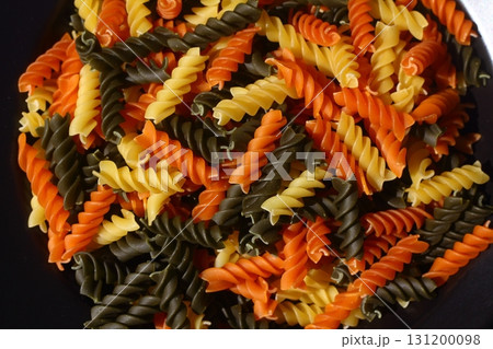 Colorful various raw fusilli on black plate Colorful various raw fusilli on black plate 131200098