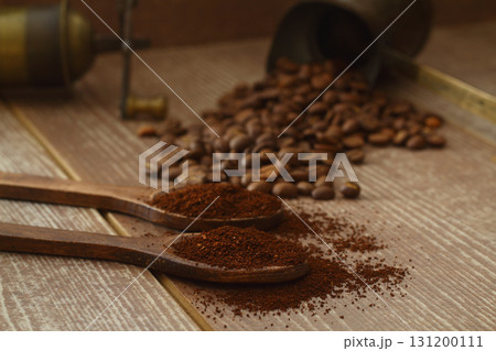 Coffee beans and ground coffee in wooden spoons on brown background. Flat lay. Coffee beans and ground coffee in wooden spoons on brown background. Flat lay. 131200111