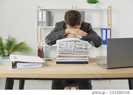 Tired male office worker dozing off leaning on stack of folders with paper documents. Tired male office worker dozing off leaning on stack of folders with paper documents. 131200150