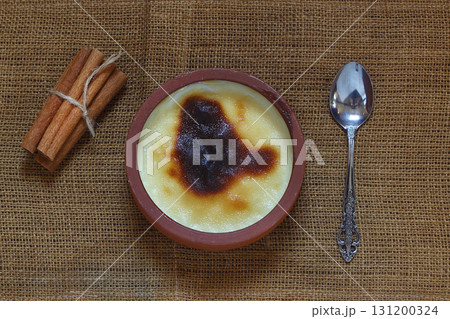 Baked rice pudding turkish dessert sutlac in earthenware casserole with cinnamon sticks 131200324