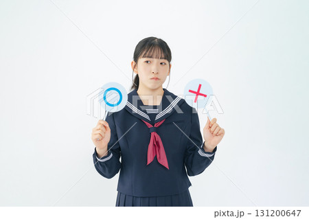 マルバツを持って悩むセーラー服を着た女子学生 131200647