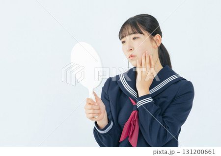 手鏡で顔を見ながら悩むセーラー服を着た女子学生 手鏡で顔を見ながら悩むセーラー服を着た女子学生 131200661