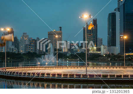 evening panorama of Bangkok city skyline with skyscrapers and Benchakitti park lake, vibrant cityscape view with reflections over pond water at dusk evening panorama of Bangkok city skyline with skyscrapers and Benchakitti park lake, vibrant cityscape view with reflections over pond water at dusk 131201365