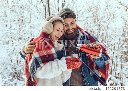 Lovely couple enjoying hot tea during a walk in a winter forest Lovely couple enjoying hot tea during a walk in a winter forest 131201878