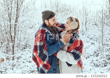 Man and woman feeling peaceful and romantic under checkered plaid in a winter forest Man and woman feeling peaceful and romantic under checkered plaid in a winter forest 131202012