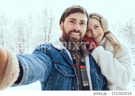 Smiling man making selfie with his girl friend in a winter forest Smiling man making selfie with his girl friend in a winter forest 131202014