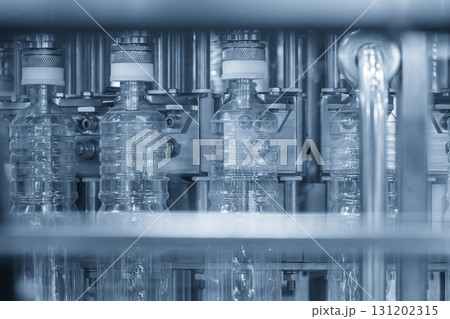 The  empty drinking water bottles on the conveyor belt for filling process in blue tone scene. 131202315