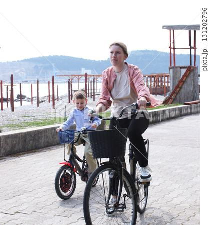cute mother with children riding on bicycles on sea side, lifestyle people 131202796