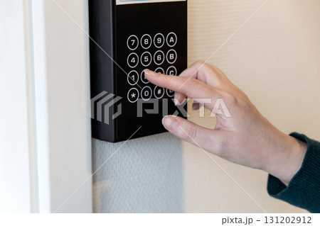 A human hand presses buttons with numbers to enter a code to open the door. A human hand presses buttons with numbers to enter a code to open the door. 131202912