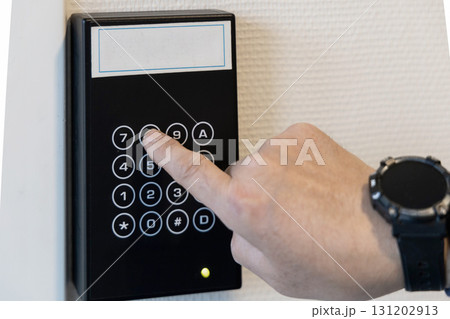 A human hand presses buttons with numbers to enter a code to open the door. 131202913