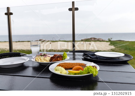 Seafood restaurant on the seashore. White plate with fish patties, fish fillets and potato salad. Seafood restaurant on the seashore. White plate with fish patties, fish fillets and potato salad. 131202915
