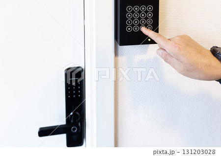 A human hand presses buttons with numbers to enter a code to open the door. 131203028