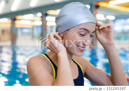 Pretty smiling young woman in a grey swimming cap at the pool Pretty smiling young woman in a grey swimming cap at the pool 131203197