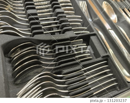 Shiny silver utensils neatly arranged in a kitchen drawer during daylight hours Shiny silver utensils neatly arranged in a kitchen drawer during daylight hours 131203237