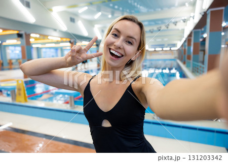 Cute smiling blonde young woman making selfie at the pool 131203342